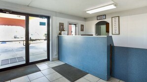 A reception area with a blue counter, a door leading outside, and a wall with a 'WELCOME' sign.