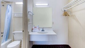 A small bathroom with a toilet, a sink, a mirror, and a shower curtain.