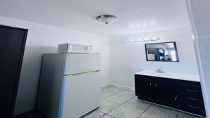 Una cucina compatta con un frigorifero, un lavello e uno specchio sopra.