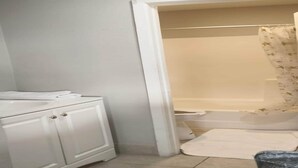 Een badkamer met een wit wastafelmeubel, toilet en douche.