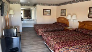 Een hotelkamer met twee bedden, een televisie, een koelkast en een zichtbare badkamer door een geopende deur.
