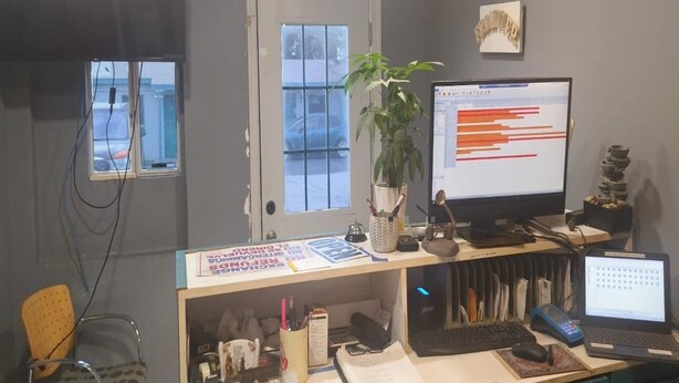 Een werkplek aan huis met een computer, een laptop, een bureau, een stoel en een potplant.