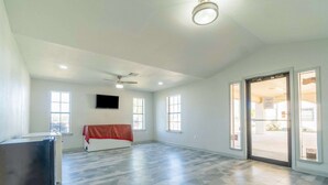 Quarto espaçoso com uma janela grande, um ventilador de teto e uma porta que dá para o exterior.