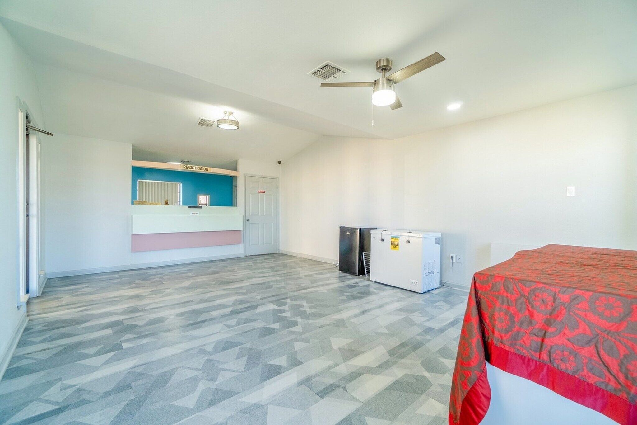 A spacious room with a registration desk, a ceiling fan, and a refrigerator.