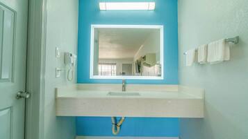 A bathroom with a blue wall, a white sink, a mirror, and a towel rack.