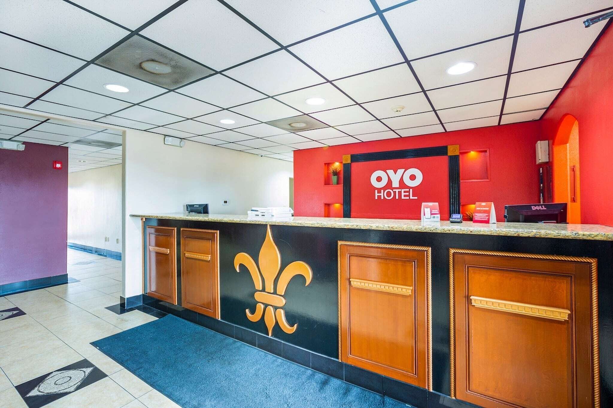 A hotel reception desk with a red and black color scheme, a fleur-de-lis logo, and a Dell computer on the counter.