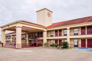 A multi-story motel with a central tower, balconies, and a covered parking area. - 2 Queen Bed | Port Allen LA (Port Allen LA)