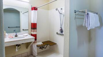 A bathroom with a shower, a sink with toiletries, a towel rack, and a mirror.