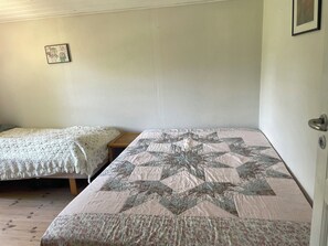 Two single beds with different quilts, a small bedside table, and a framed picture on the wall. - Holiday Close to Forest, Fjord and Beach (Kulhuse)