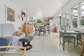A spacious room with a dining area, a kitchen, and a seating area with a patterned chair and ottoman. - Holiday Close to Forest, Fjord and Beach (Kulhuse)