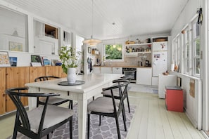 Una cocina con una isla central, muebles blancos y una estufa roja.
