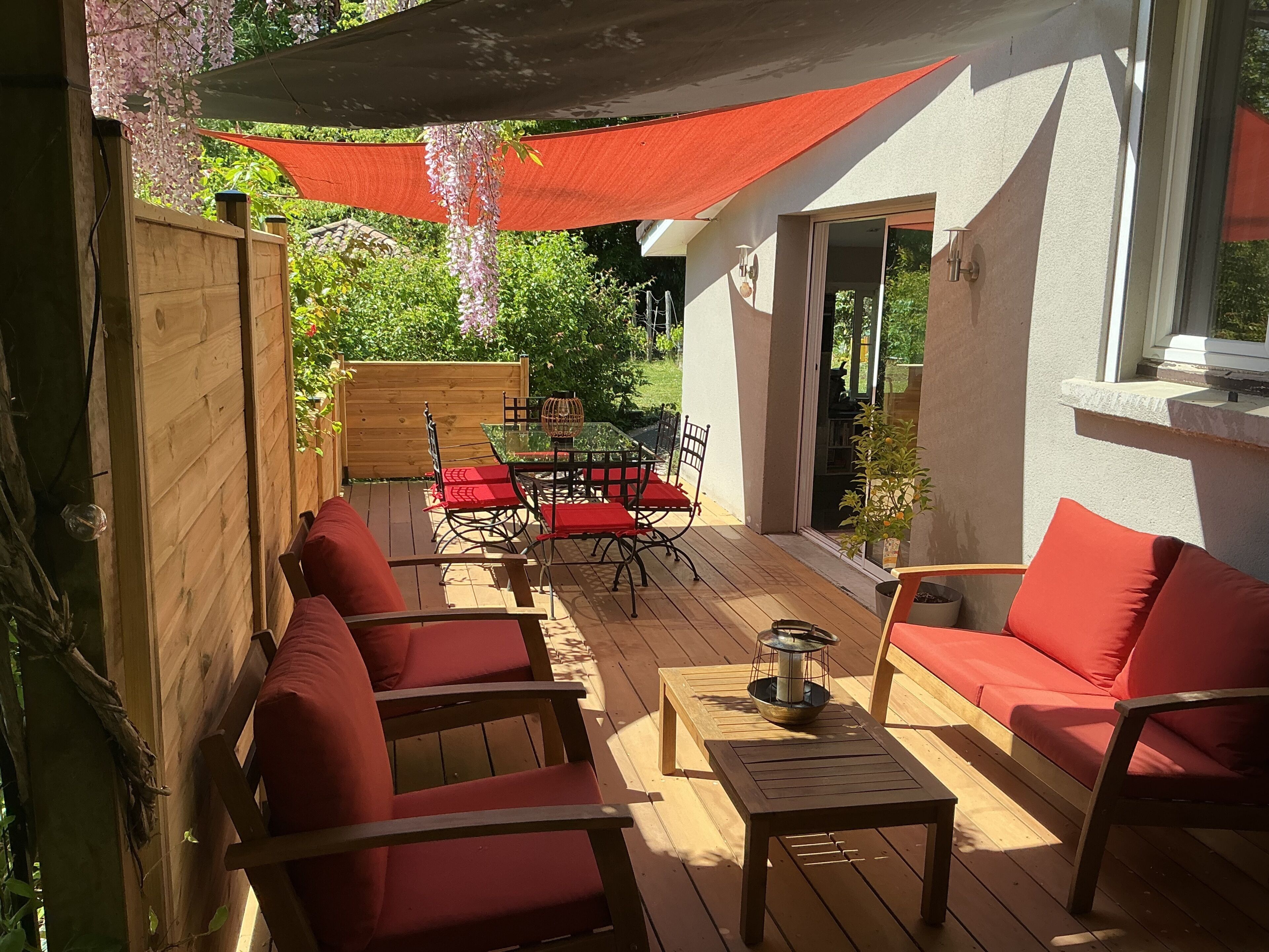 Une terrasse extérieure avec des meubles en bois, une table avec une bougie et un auvent rouge.