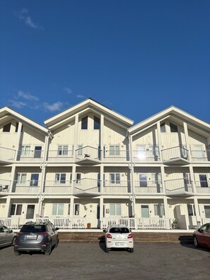 Un immeuble à plusieurs étages doté de balcons et d’un espace de stationnement.