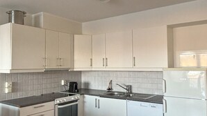 Una cocina con armarios blancos, estufa, lavaplatos y refrigerador.
