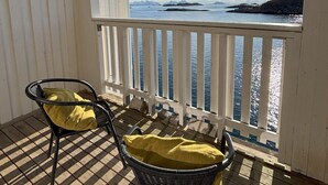 Un balcón con dos sillones de mimbre, piso a cuadros y vista al mar.