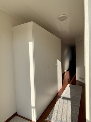 Un couloir avec une armoire blanche, un plancher en bois et un tapis blanc.