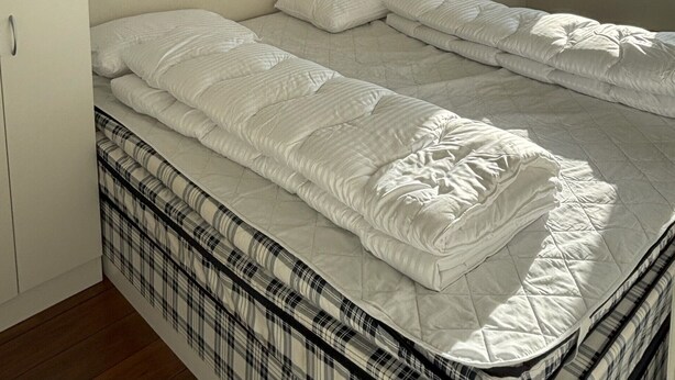 Un dormitorio con una cama, un ventanal y un armario.
