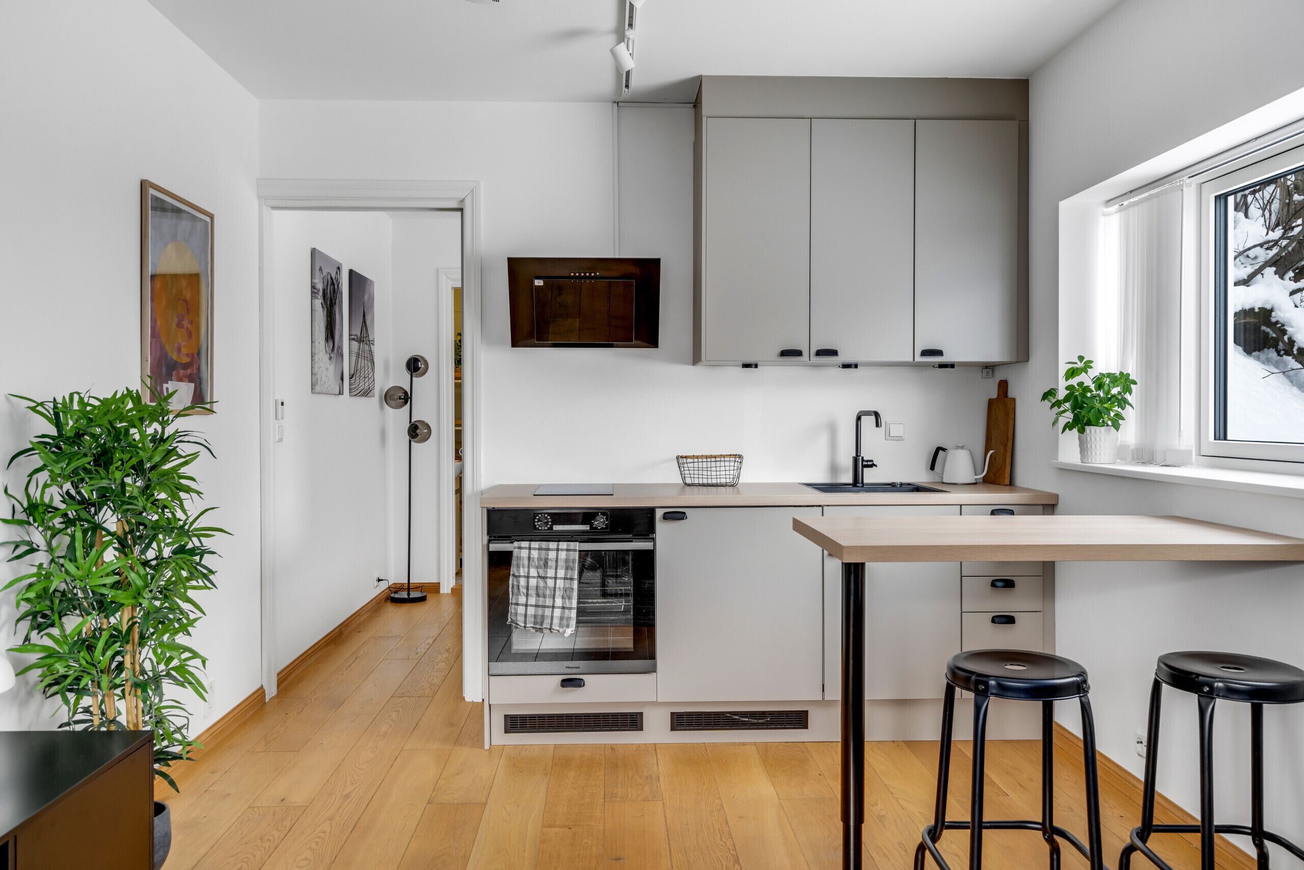 A modern kitchen with a built-in oven, a microwave, and a window with a view of snow.