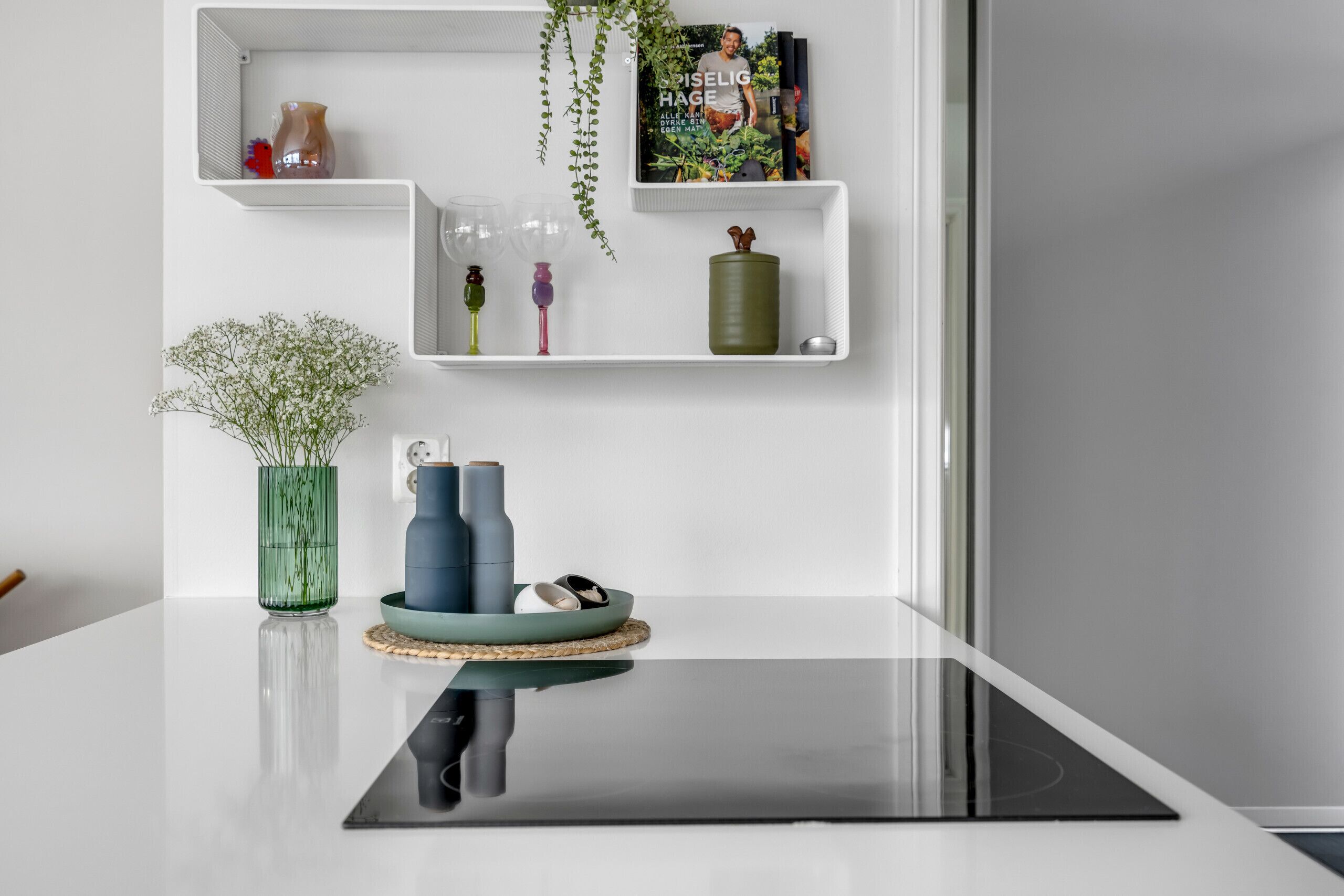 A modern kitchen with a black countertop, white shelves, and various kitchen items.