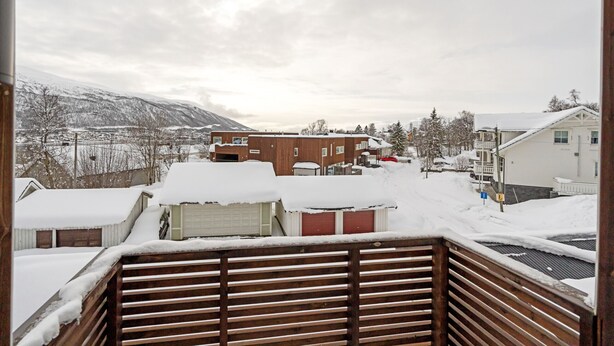 A residential area with houses covered in snow, a wooden deck, and a mountain in the background. - Northern Luxe Retreat (Tromsø)