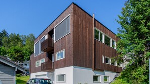 A modern two-story building with a wooden facade, large windows, and a balcony. - Northern Luxe Retreat (Tromsø)