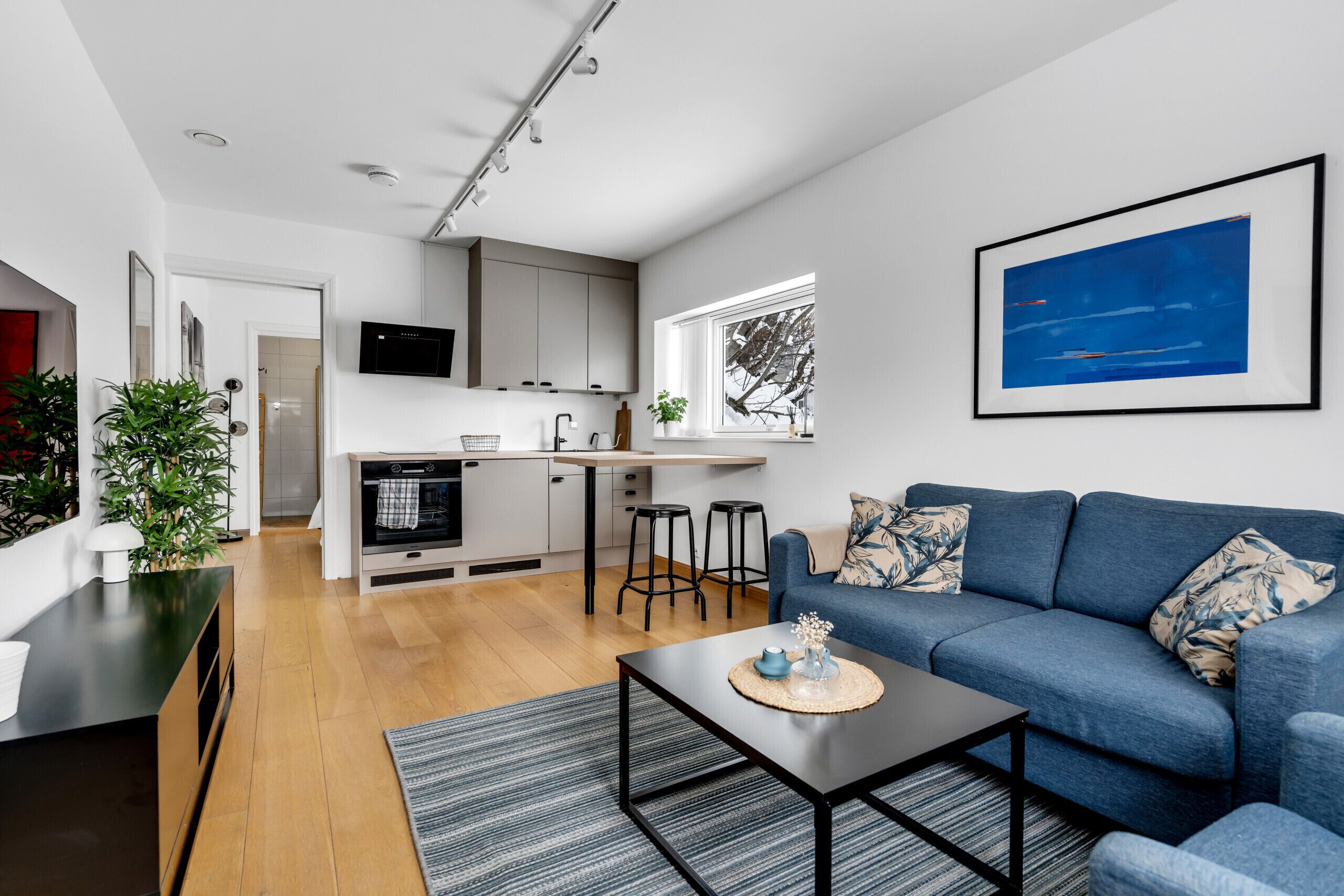 A modern living space with a kitchen, a dining area, and a seating area with a sofa and coffee table.