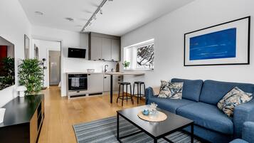 A modern living space with a kitchen, a dining area, and a seating area with a sofa and coffee table.
