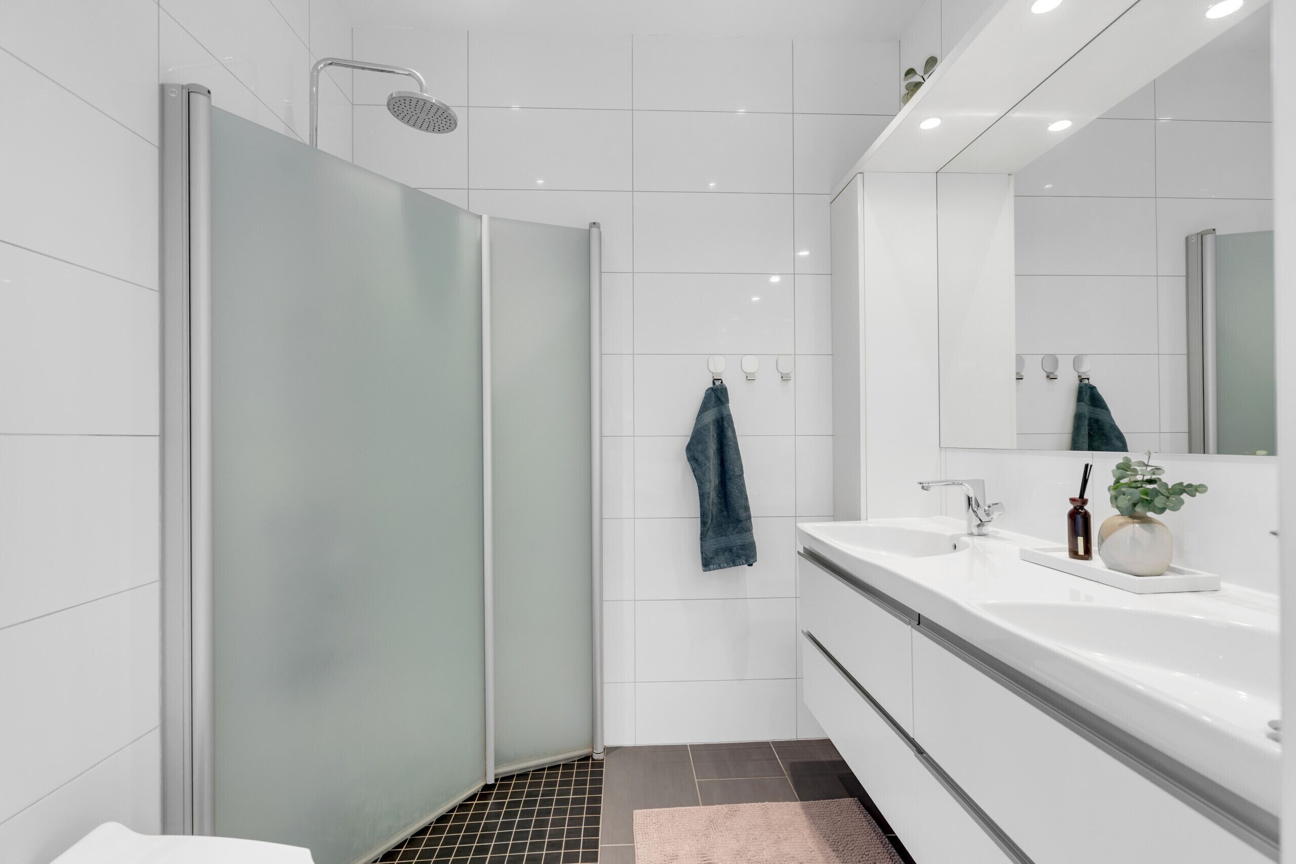 A modern bathroom with a glass shower enclosure, a white sink, and a large mirror.