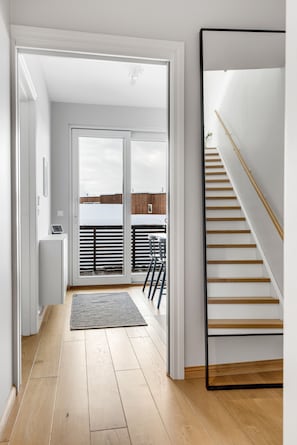 A modern interior with a wooden floor, a staircase, and a view of the outside.