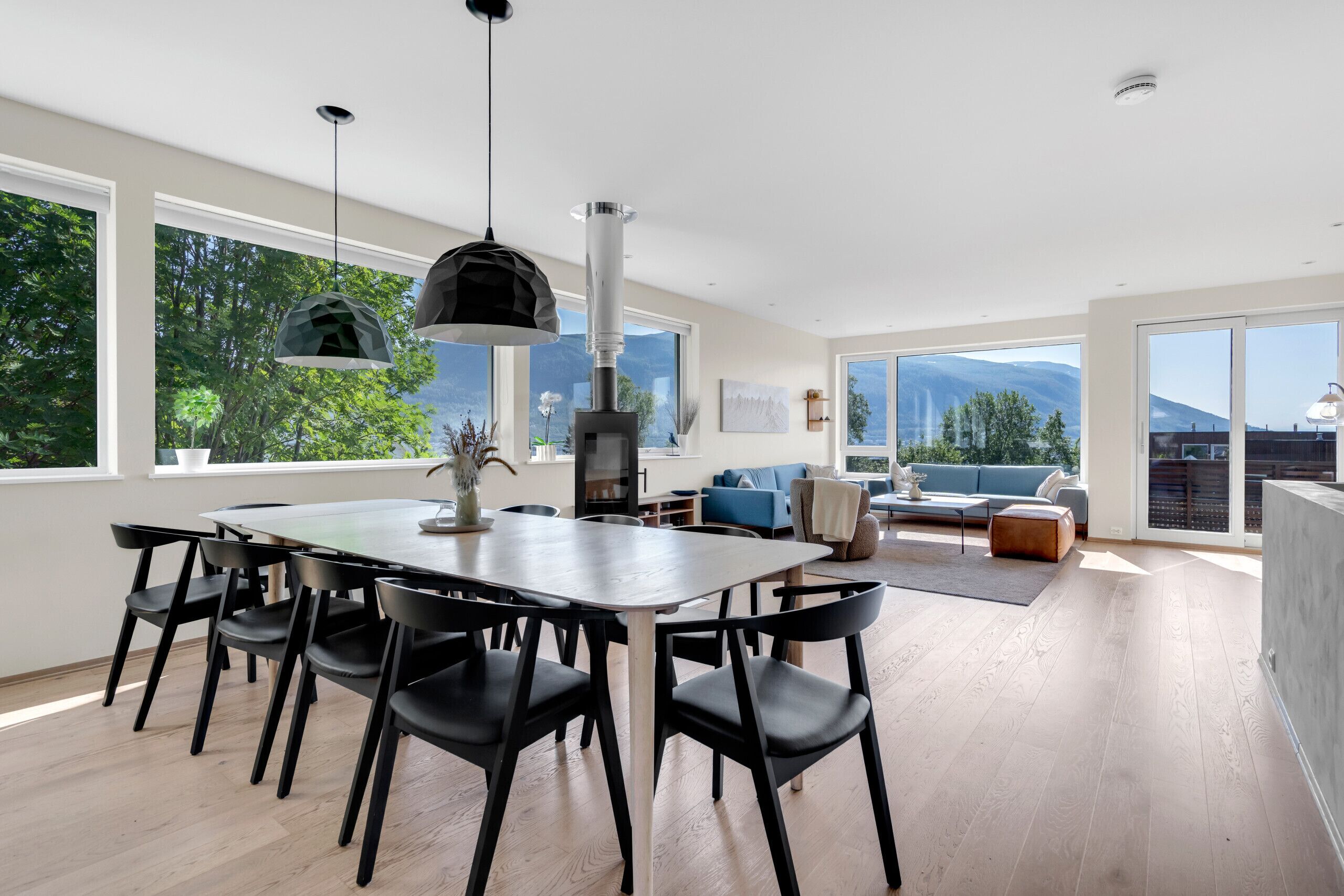 Een moderne eethoek met een grote tafel en stoelen, een hangende lamp en uitzicht op de omgeving.