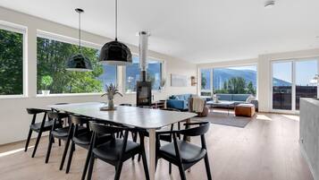 Un comedor moderno con una mesa grande y sillas, una lámpara colgante y vistas al exterior.