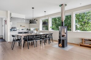 A modern kitchen with a central island, pendant lighting, and a large window overlooking greenery. - Northern Luxe Retreat (Tromsø)