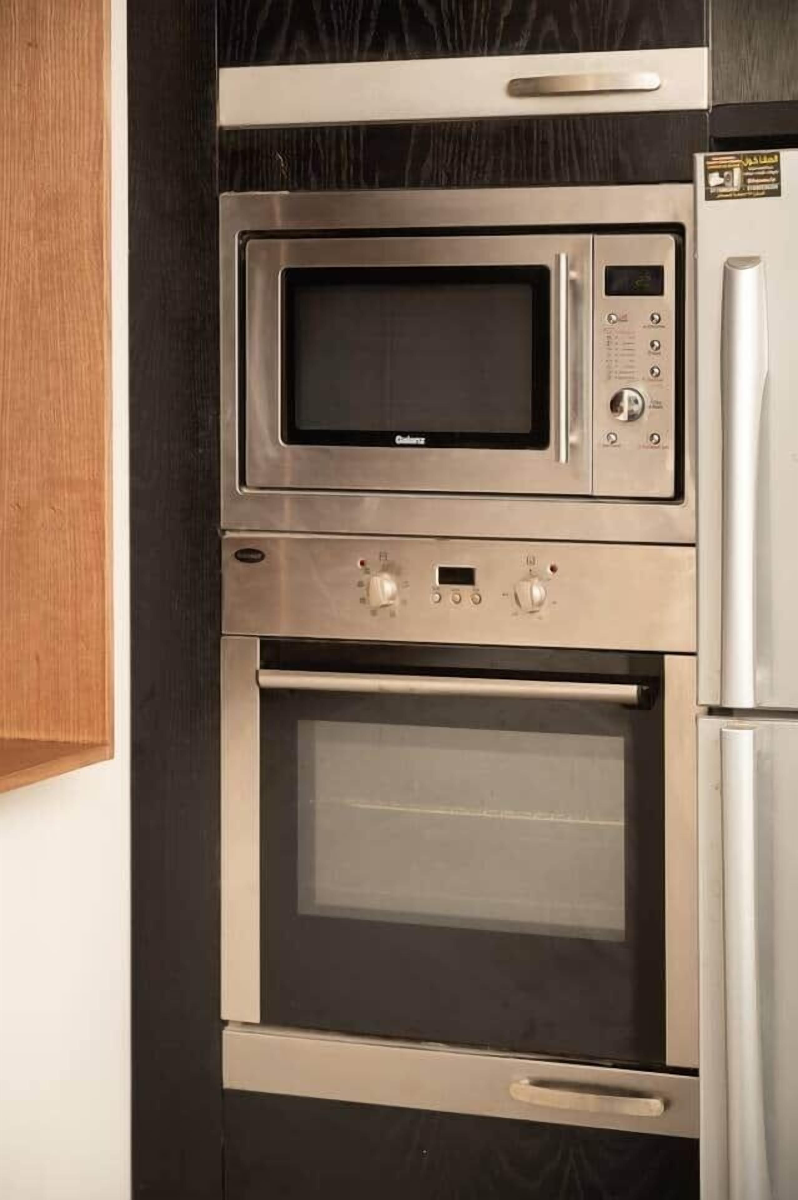 A kitchen with a microwave, oven, and refrigerator.