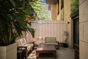 A patio area with a sofa, a wooden table, and potted plants. - Olive & Oak Residence I Nesty Hospitality (Al Maadi)