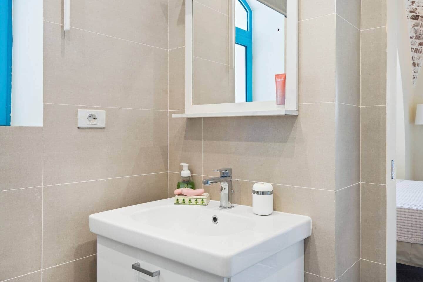 Une salle de bain avec un lavabo blanc, un miroir et un porte-serviettes.
