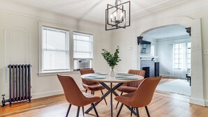 Un comedor con una mesa redonda, seis sillas, una planta en el centro y una araña.