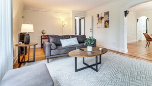 Una sala de estar con sofá, mesa de centro, lámpara y una alfombra estampada.