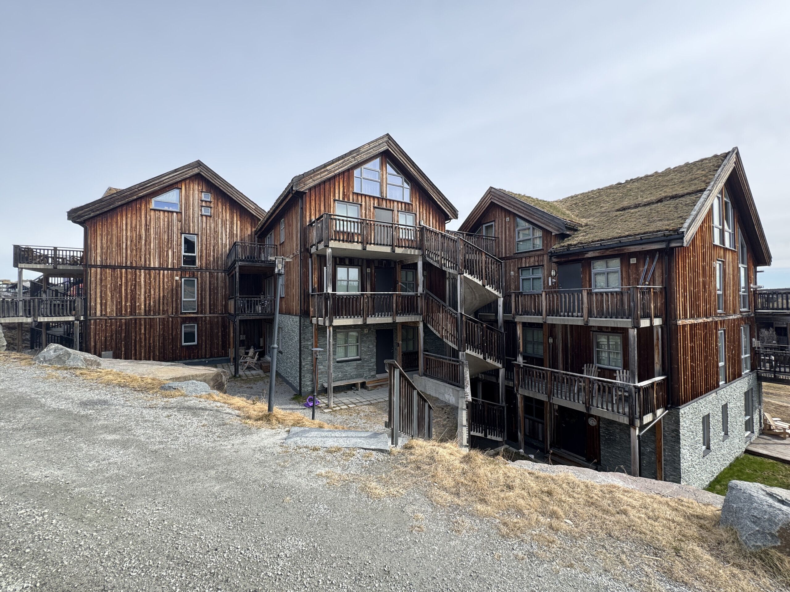 A wooden multi-story building with balconies and a stone base.