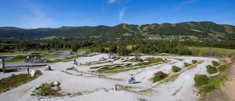 Un sendero para ciclismo de montaña bajo un cielo despejado y colinas distantes.