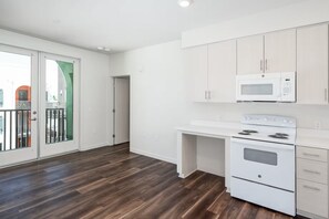 A modern kitchen with white cabinets, a microwave, and a stove.