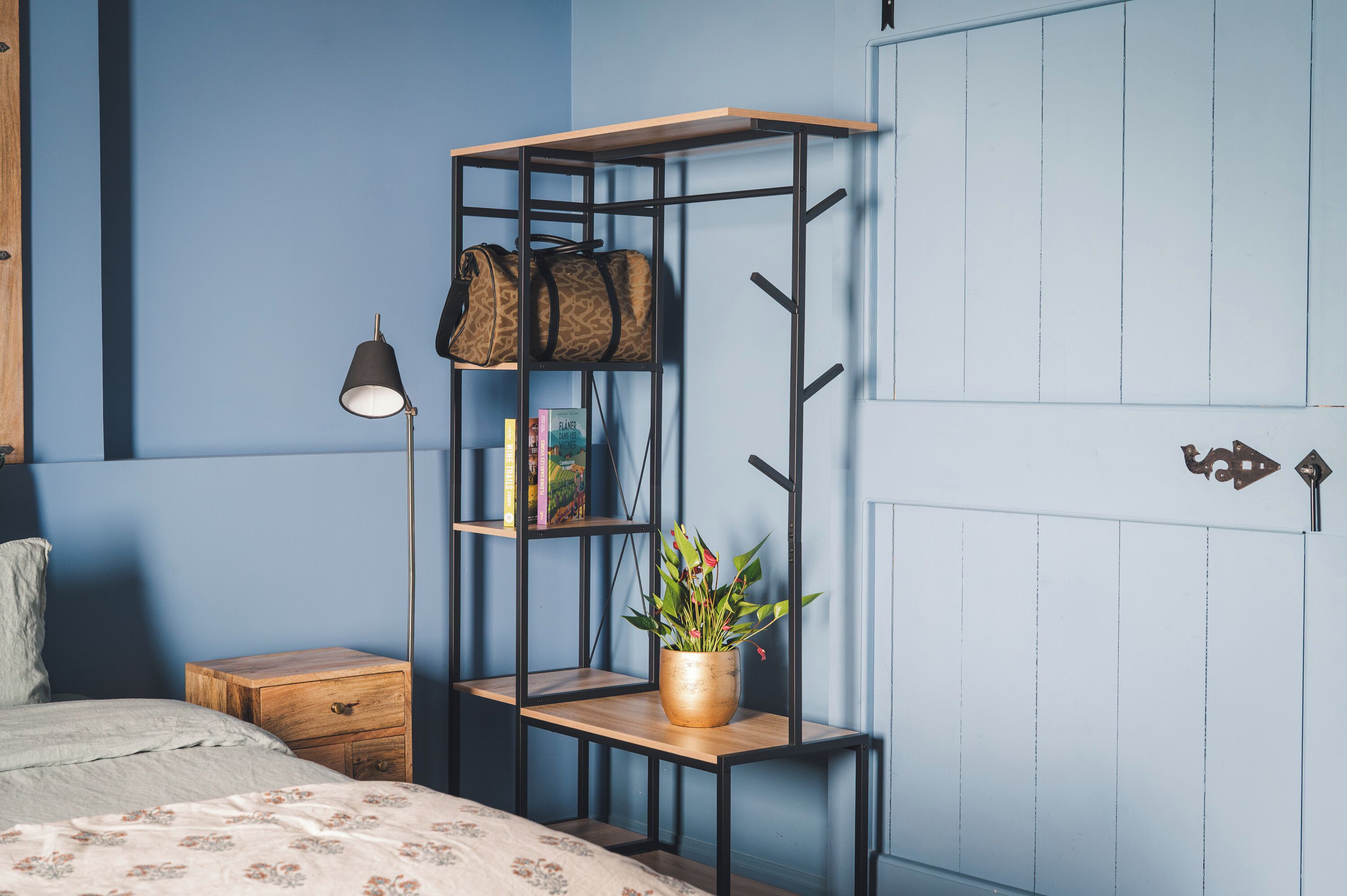 A bedroom with a bed, a nightstand, a bookshelf, a lamp, and a wardrobe.