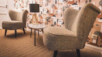 Een kamer met twee fauteuils, een klein rond tafeltje en een lamp.