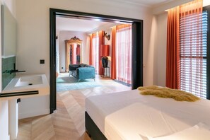Une chambre d’hôtel avec un lit, un canapé, un miroir et une vue sur une autre chambre.