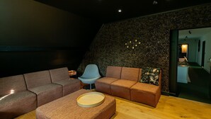 A modern living room with a sectional sofa, a round ottoman, and a blue armchair. - Luxury family villa in Bilzen - Villa Alba (Bilzen)