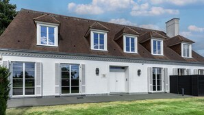 A two-story house with a gabled roof, multiple garage doors, and a chimney. - Luxury family villa in Bilzen - Villa Alba (Bilzen)