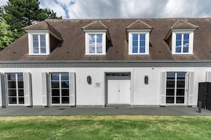Un bâtiment à deux étages, doté d’une façade blanche, de nombreuses fenêtres et d’une porte de garage.