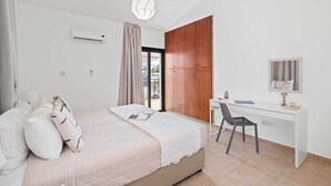 Een slaapkamer met een bed, een bureau, een stoel, een kledingkast en een hanglamp.