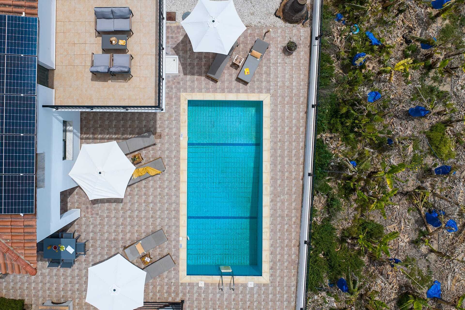 An aerial view of a rooftop pool area with lounge chairs and umbrellas.