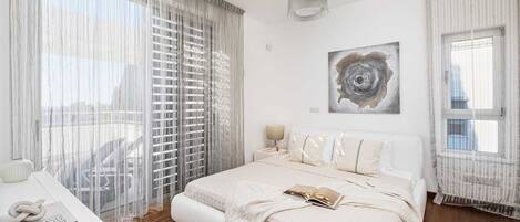 A bedroom with a bed, a bedside table, a lamp, and a window with curtains.