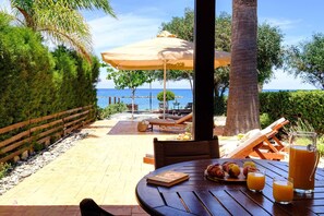Patio con tavolo apparecchiato per la colazione, vista sulla spiaggia.